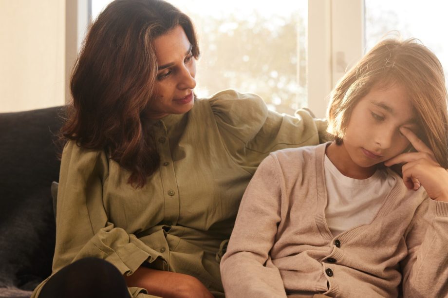 En mamma sitter i en soffa och pratar med sin son som gnider sig ögonen och tittar bort. Trötthet och koncentrationsbesvär är vanliga symtom på pollenallergi.